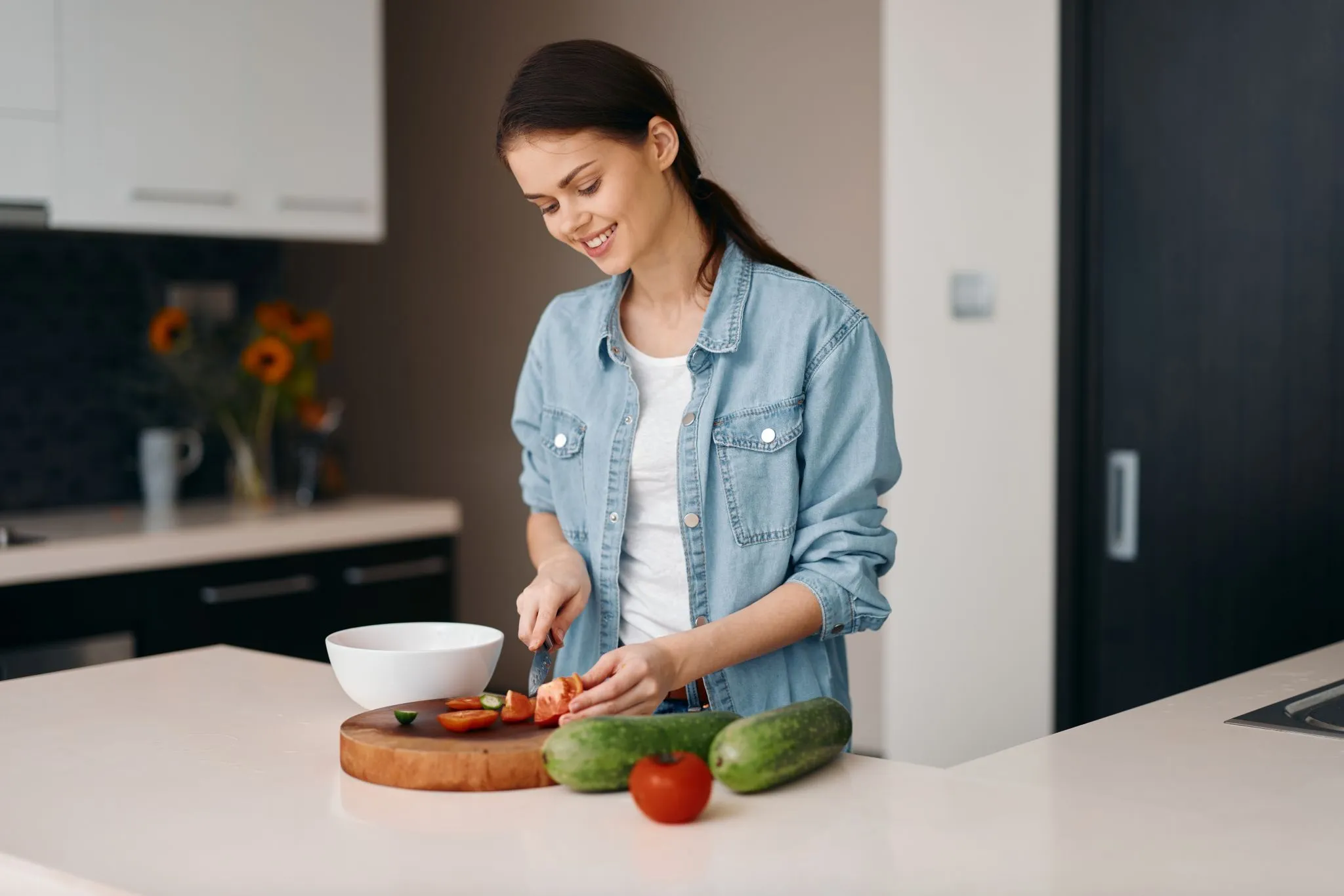 Avery Collins smiling as she chops fresh tomatoes and cucumbers for a healthy recipe.