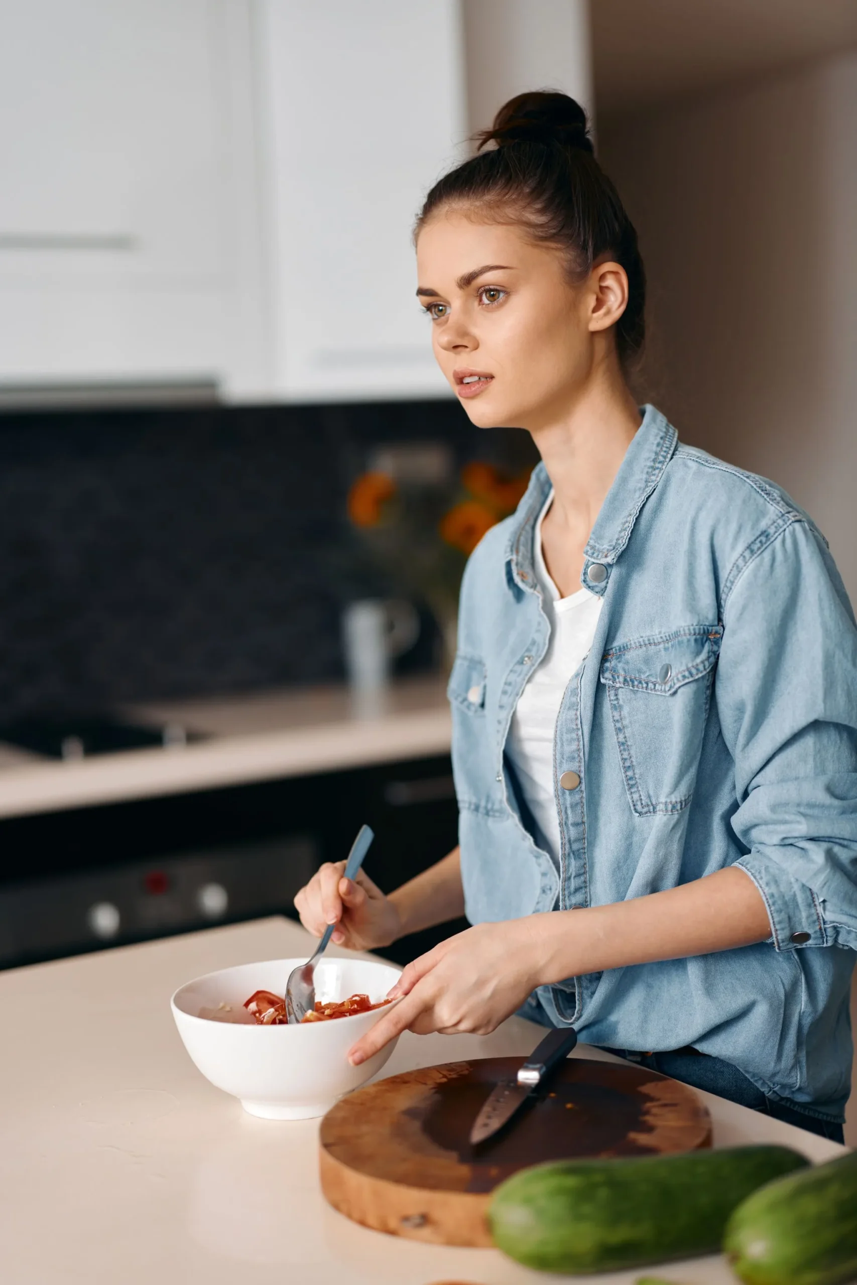 Avery Collins, founder of Devour Dish, thoughtfully mixing a salad in her kitchen.