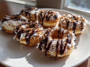 A plate of freshly made apple samoas donuts topped with shredded coconut, caramel, and chocolate drizzle.