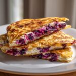 Close-up of a stacked blueberry breakfast quesadilla, showing the creamy filling and bursting blueberries.