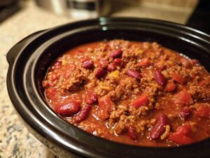 Close-up of a slow cooker filled with delicious Crockpot chili, featuring ground beef, kidney beans, and tomatoes.
