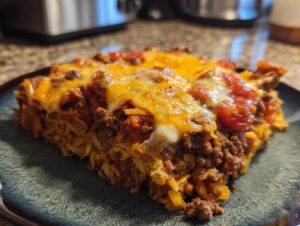 A close-up of a hearty slice of Dorito Casserole, featuring layers of seasoned ground beef, crushed Doritos, and melted cheese.