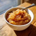 A close-up of a bowl of warm, chunky homemade applesauce sprinkled with cinnamon.