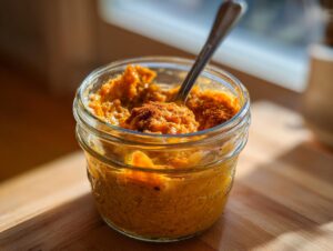 A close-up of delicious Pumpkin Overnight Oats in a glass jar, topped with cinnamon and a spoon.