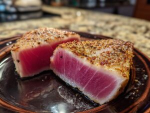 Close-up of two perfectly seared tuna steaks, showing a vibrant pink interior and a seasoned crust.