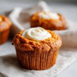 Close-up of a Starbucks pumpkin cream cheese muffin topped with a swirl of cream cheese frosting.