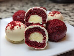 Close-up of amazing red velvet cake pops, one cut in half showing the creamy white center filling.