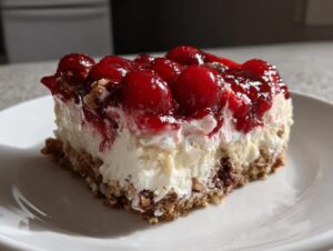 A decadent slice of Cherry Pecan Cheesecake Lush on a white plate, featuring a creamy filling, cherry topping, and pecan crust.