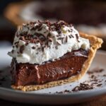 A decadent slice of Christmas chocolate pie topped with fluffy whipped cream and chocolate shavings.