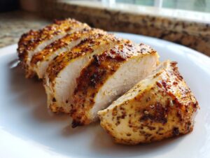 Close-up of perfectly cooked, sliced greek chicken breast showing moist interior and seasoned crust.