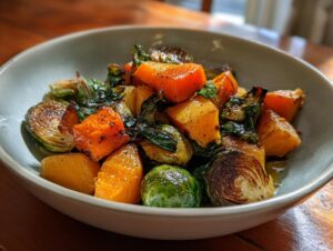 A bowl of roasted butternut squash and Brussels sprouts, showcasing a delicious plant based fall recipe.