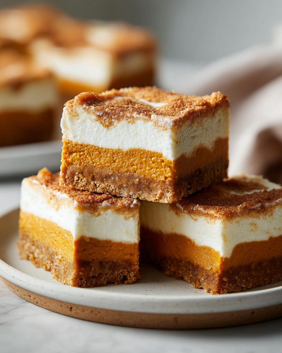 A stack of three delicious pumpkin cheesecake bars with a creamy white topping and graham cracker crust.