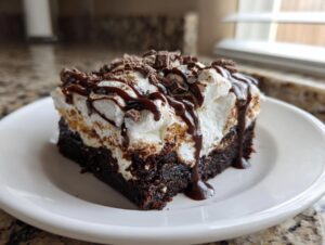 A single serving of rich chocolate poke cake topped with whipped cream, chocolate drizzle, and shavings.