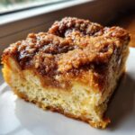 A close-up of a moist slice of french toast casserole featuring a thick, gooey cinnamon streusel topping.