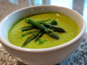 Close-up of bright green creamy asparagus soup topped with whole, tender asparagus spears.