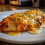 Close-up of a juicy piece of Fiesta Lime Chicken topped with melted orange cheddar and white cheese, sprinkled with herbs.