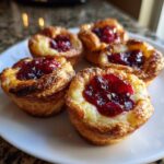 Five golden-brown baked brie bites topped with a dollop of bright red cranberry jam, ready to eat.