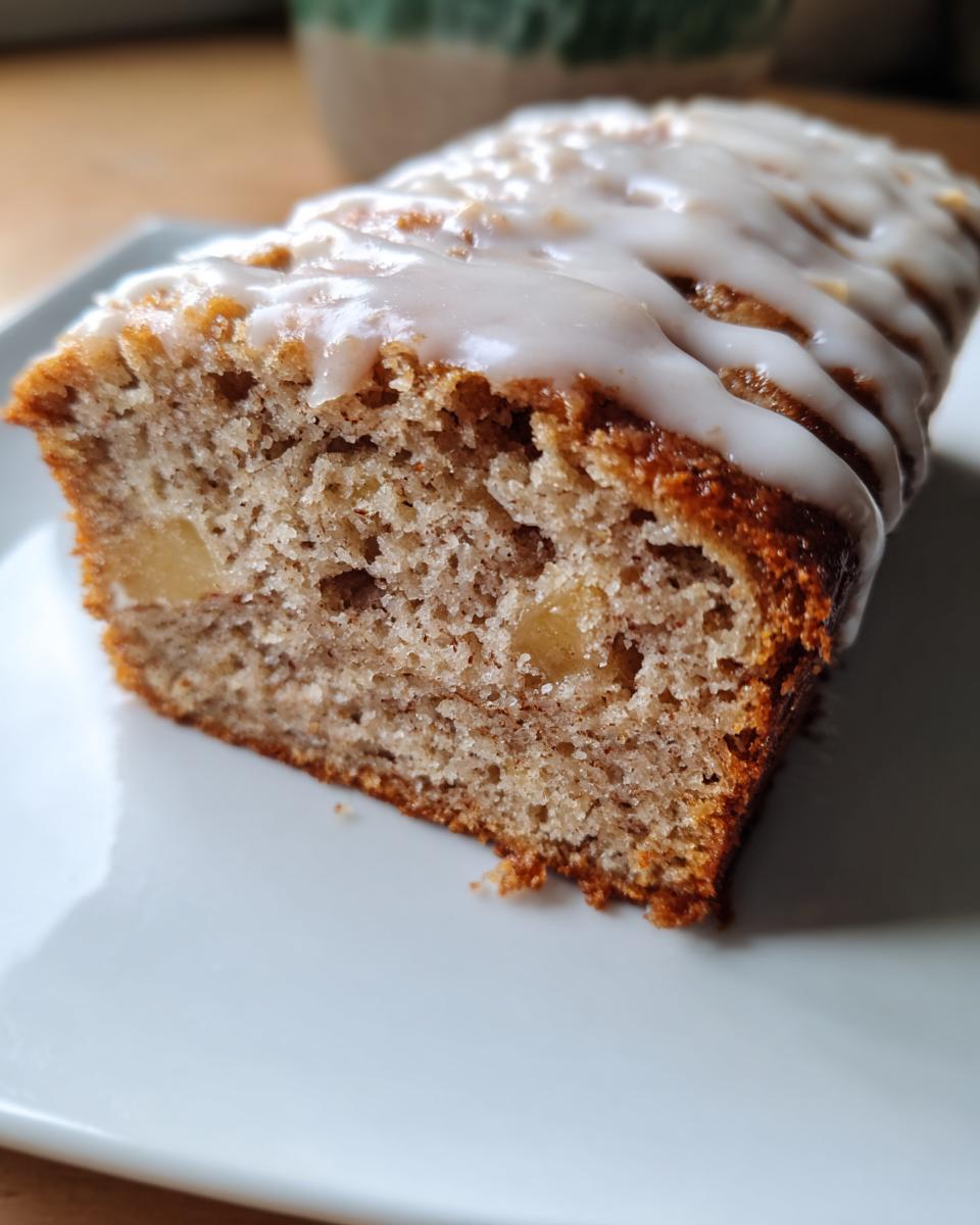 Cross-section of moist apple bread loaf topped with a white vanilla glaze.