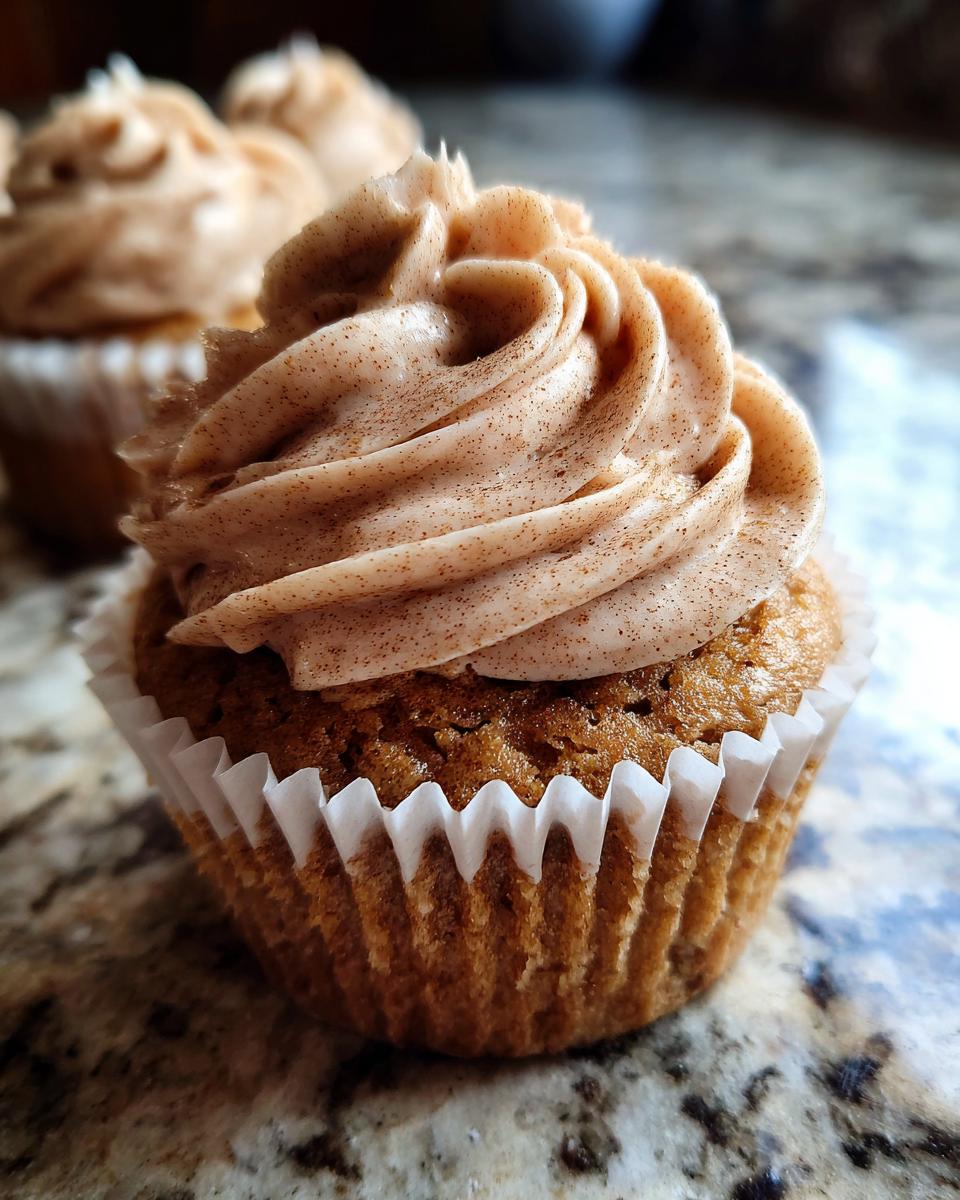 Close-up of a moist banana cupcakes topped with a swirl of cinnamon-flecked frosting.