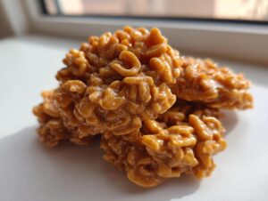A stack of shiny, peanut-butter colored no-bake haystack cookies made with chow mein noodles.