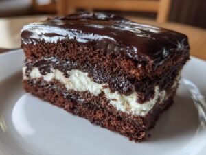 Close-up of a decadent slice of chocolate italian love cake featuring dark cake layers and a thick white cream filling, topped with glossy ganache.