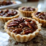 A close-up shot of one of the amazing mini pecan pies, showing the gooey filling and pecan topping.