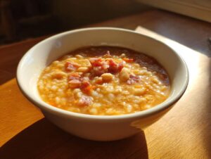 Close-up of a creamy bowl of amazing navy bean soup topped with diced ham and carrots.