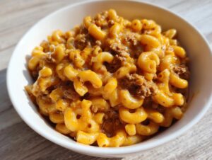 Close-up of a white bowl filled with creamy, cheesy homemade hamburger helper and ground beef.