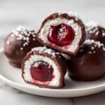 Close-up of chocolate covered cherries cut in half, showing the white filling and bright red cherry center.