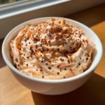 A white bowl filled with creamy, pinkish-orange smoked salmon dip, topped with everything bagel seasoning.