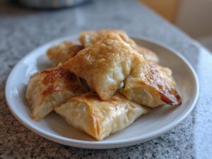 A pile of golden brown, crispy rice paper dumplings served on a small white plate.