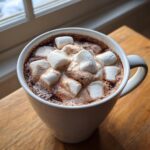 A cozy mug filled with rich crockpot hot chocolate recipe topped generously with melting marshmallows.