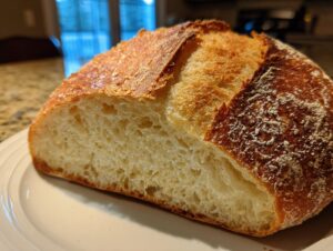 Close-up of a freshly baked french bread loaf, showing the open, airy crumb and golden, crisp crust.