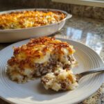A serving of french onion ground beef and rice casserole with a crispy onion topping on a white plate.