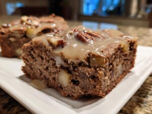 A close-up of a rich, fudgy apple brownies square topped with caramel glaze and pecans.