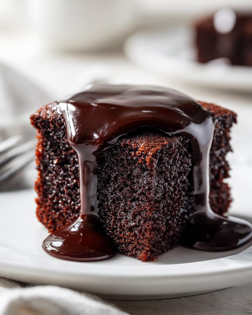 Close-up of a moist slice of chocolate pudding cake drenched in rich, dark chocolate sauce.