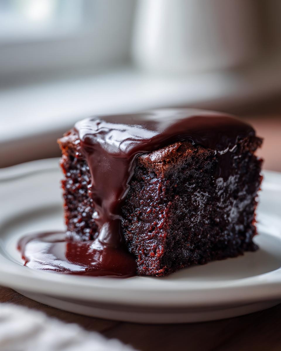 A moist, dark square of chocolate pudding cake topped with rich, glossy chocolate sauce.