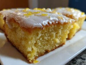 A close-up shot showing the moist, yellow crumb of baked lemon brownies topped with white glaze and lemon zest.