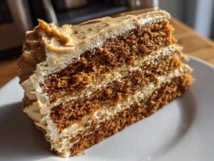 A close-up of a moist slice of gingerbread latte cake showing three layers of dark cake and coffee-colored frosting.