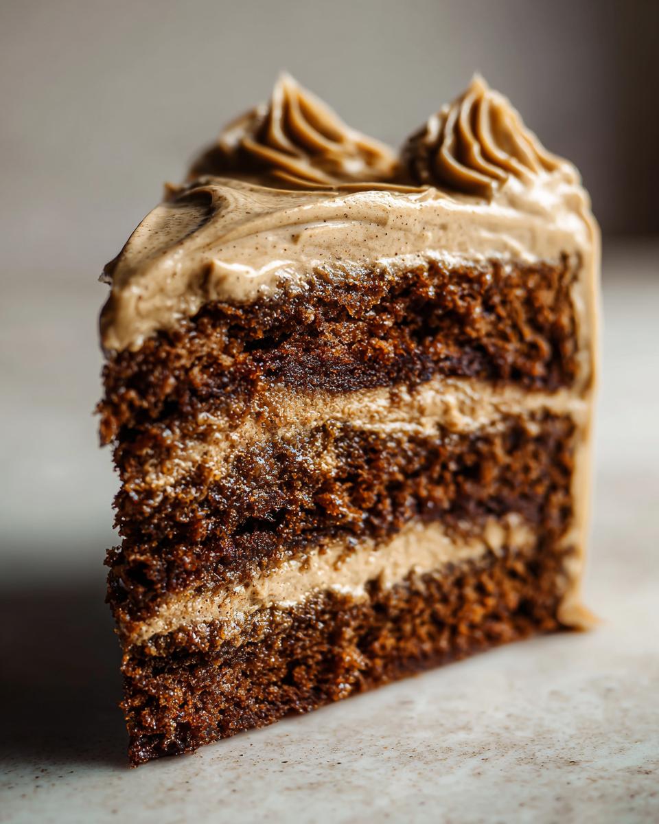 Close-up of a multi-layered slice of moist gingerbread latte cake with thick coffee-colored frosting.