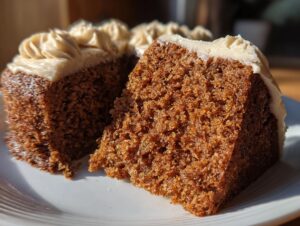 Close-up of a moist slice cut from a round spice cake, topped with piped cream cheese frosting.
