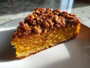 Close-up of a moist slice of pumpkin crunch cake featuring a rich orange color and crunchy pecan topping.