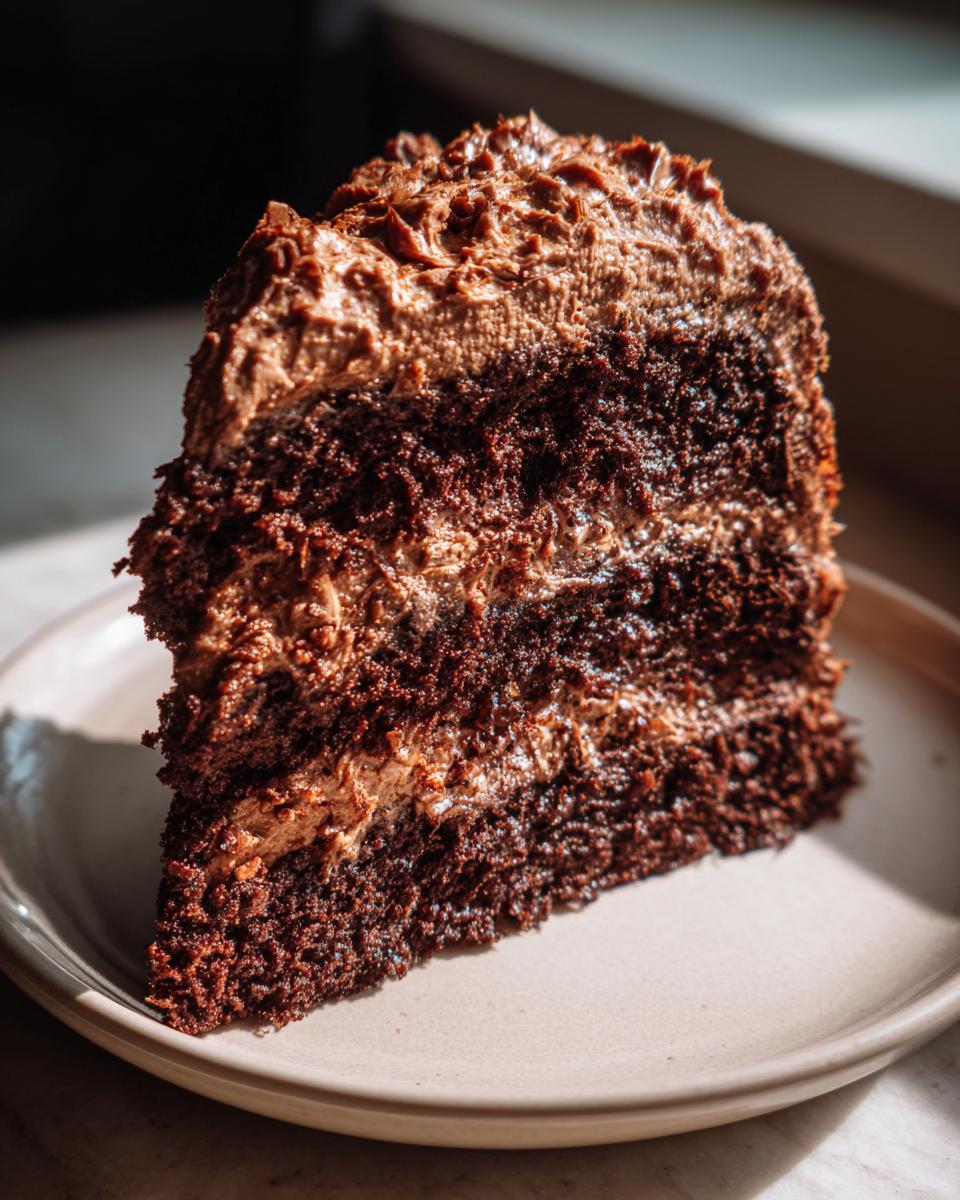 A decadent slice of german chocolate cake recipe showing dark chocolate layers and thick chocolate frosting.