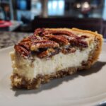 A close-up shot of a thick slice of pecan cream pie showing the creamy white filling and pecan topping.