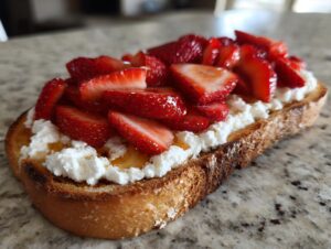 Close-up of sweet cottage cheese toast topped with sliced strawberries and a drizzle of honey.