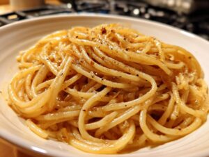 A close-up shot of a creamy bowl of spaghetti tossed in a rich sauce, featuring caramelized onion pasta and black pepper.