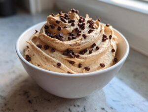 A white bowl filled with creamy, swirled peanut butter dip topped generously with mini chocolate chips.