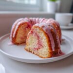 A slice of moist hello kitty cinnamon roll cake with pink swirl filling and thick pink glaze dripping down the side.